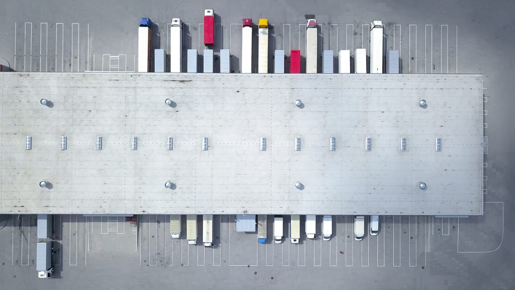 vista aérea de bodega logística industrial con camiones
